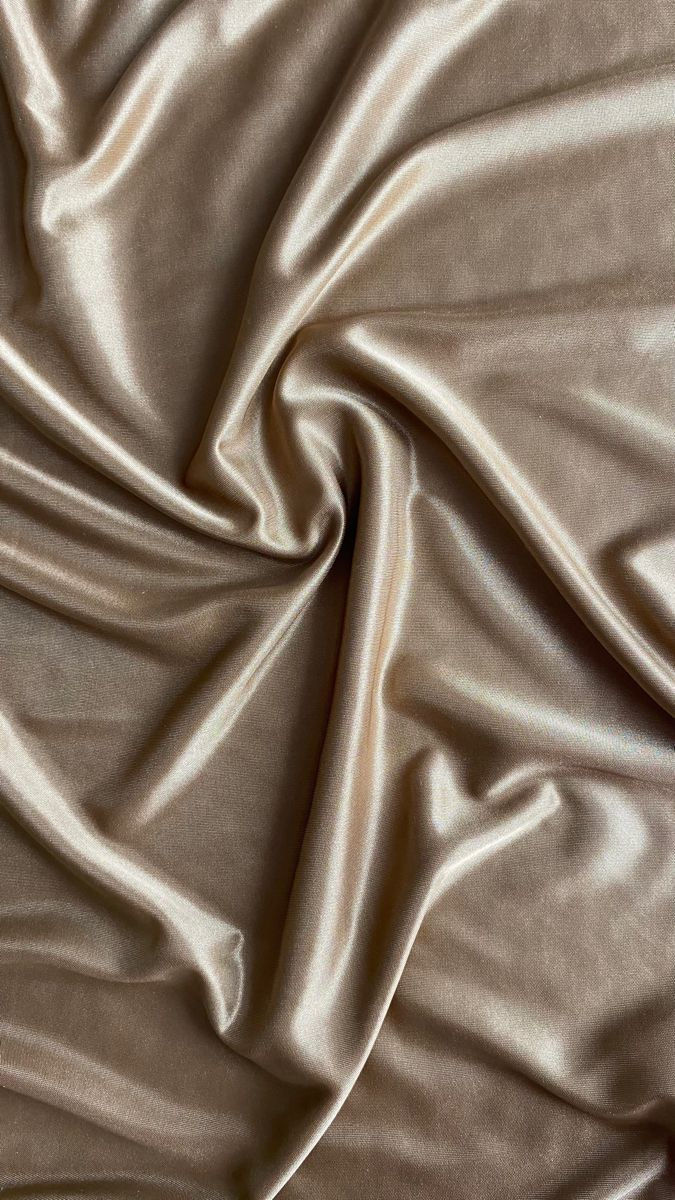 Close-up of beige velvet with soft folds and warm highlights that emphasize its texture and drape.