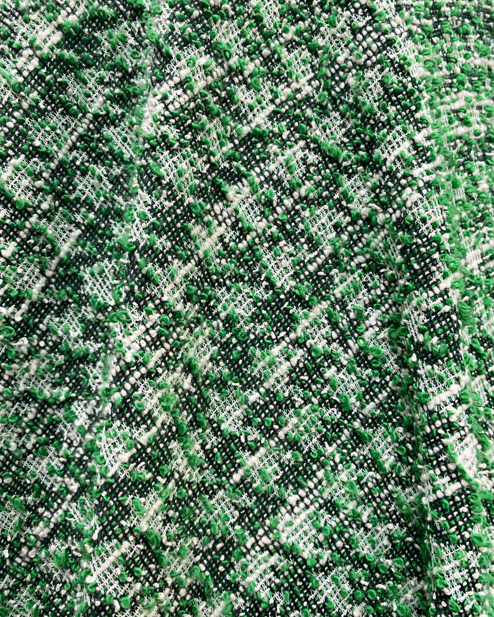 Close-up of the green tweed fabric, highlighting its woven texture, colour interplay, and sophisticated structured appearance.