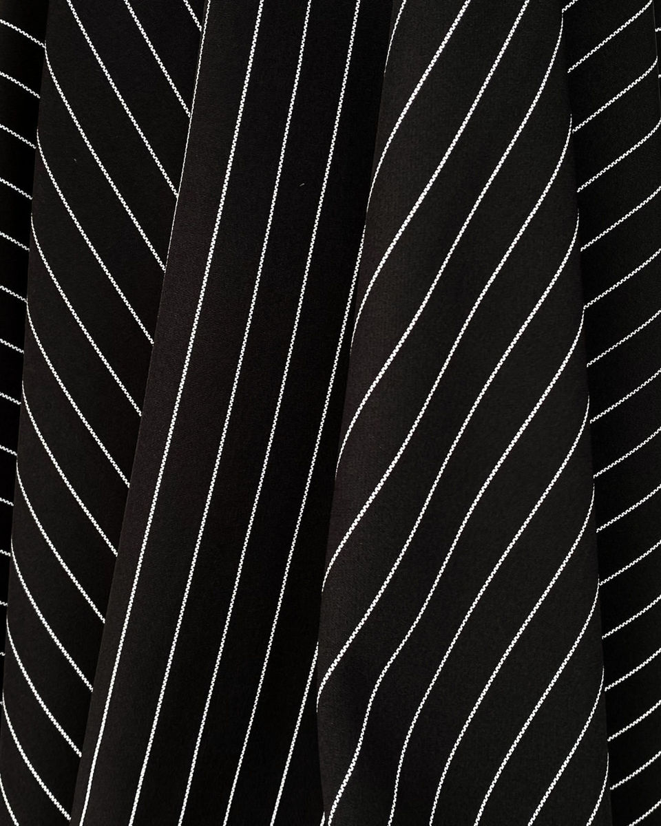 Close-up of black fabric with fine white pinstripes, arranged in soft folds.